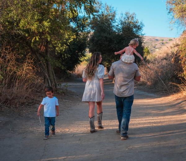 Family walking down a dirt trail together at golden hour