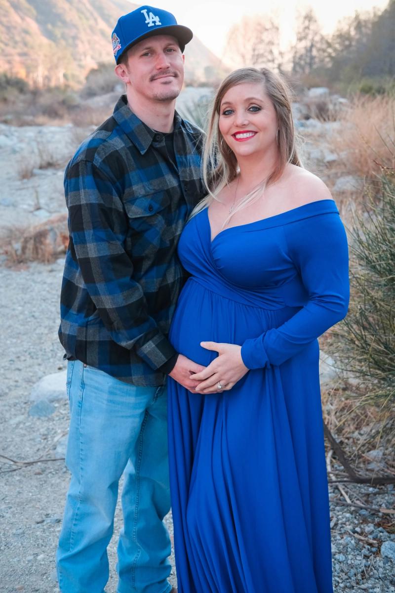 Dad in a ball cap holding his partner and her bump
