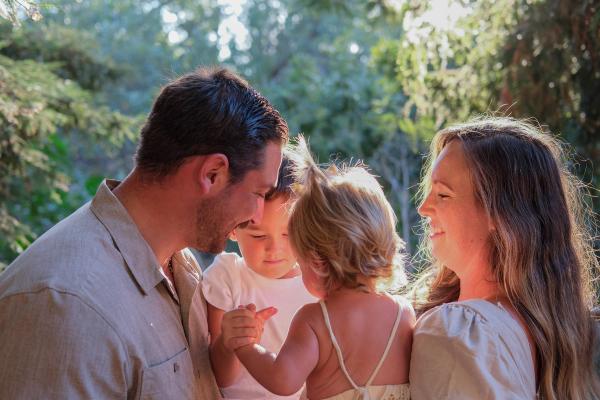 Family snuggled close, cheek to cheek, in warm backlight