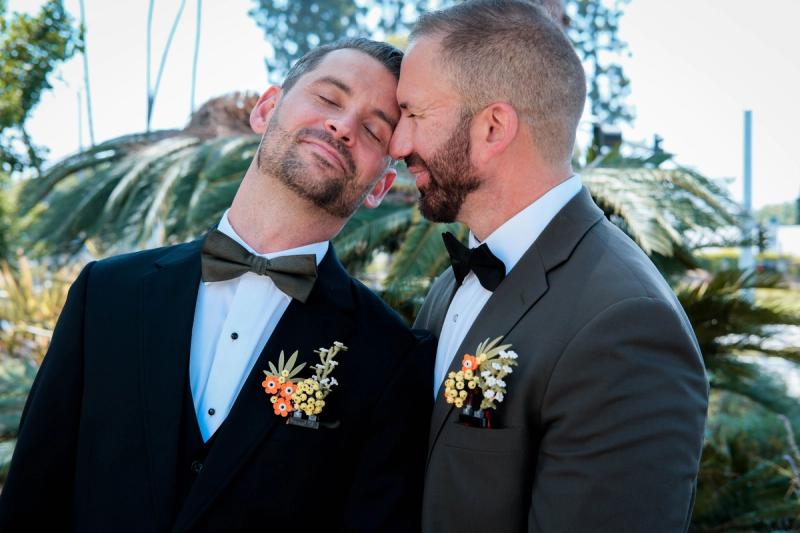 Newlyweds laughing cheek to cheek among tropical plants