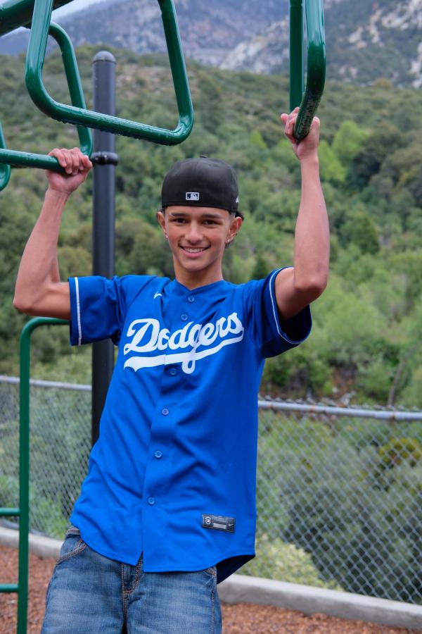 Teen in a Dodgers jersey hanging from the playground bars