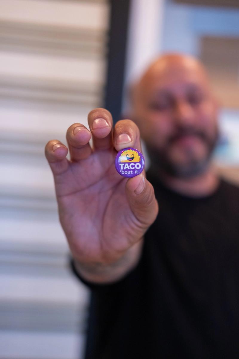 Owner holding out a Taco Bout Good sticker toward the camera