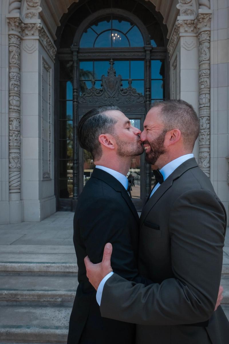 Grooms kissing at the carved doors of Beverly Hills City Hall