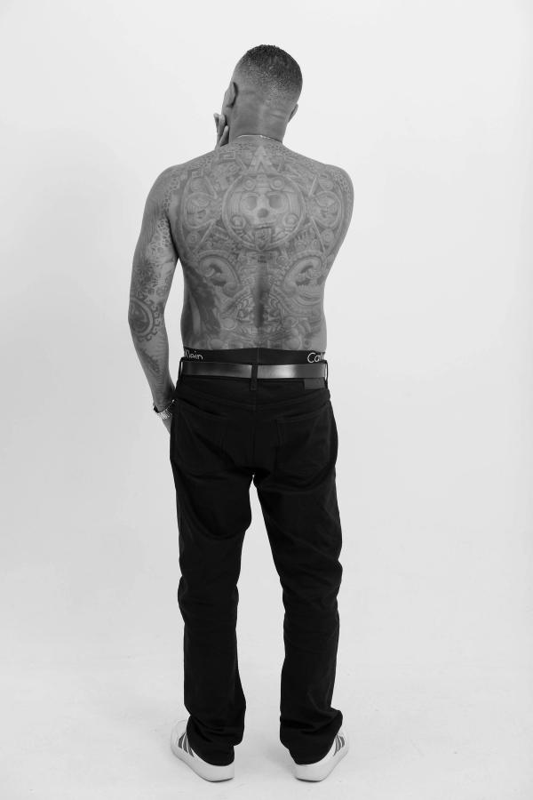 Black and white portrait from behind showing a full back tattoo