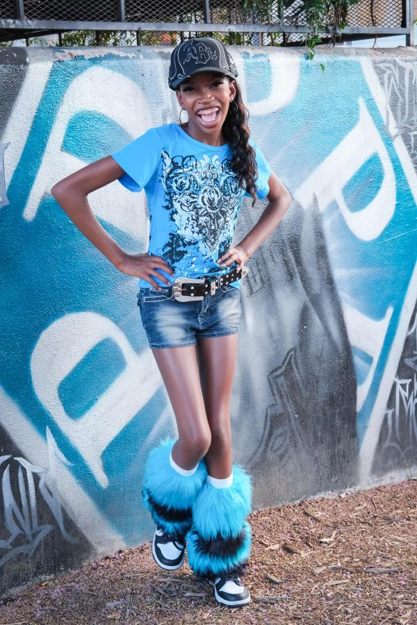 Girl in fuzzy blue boots posing with a hand on her hip by a mural