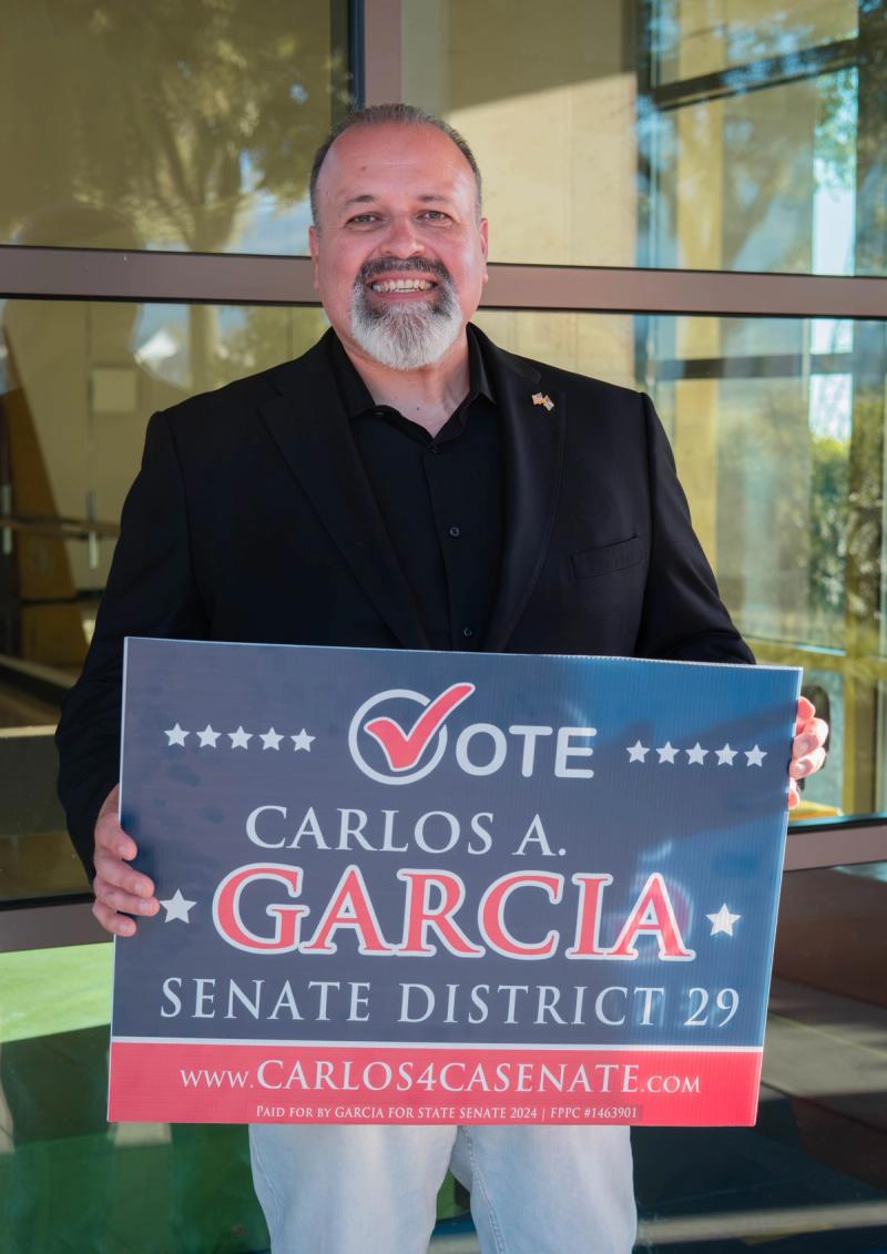 Candidate holding a "Vote Carlos A. Garcia, Senate District 29" sign