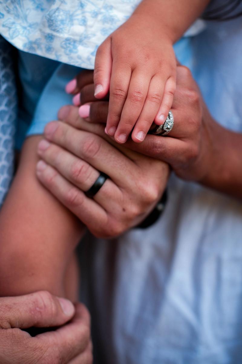 Close-up of the parents’ hands and wedding rings