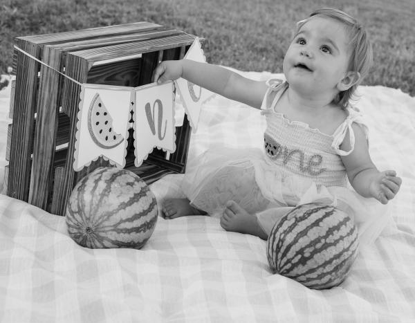 Black and white photo of a little girl reaching toward her first birthday banner