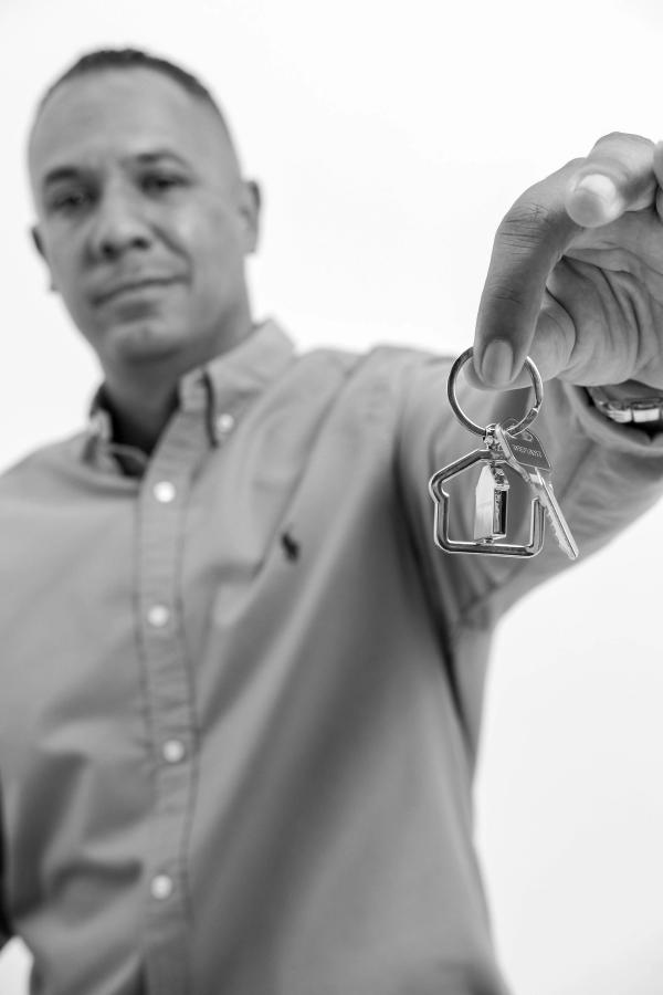 Smiling man holding a set of house keys out toward the camera