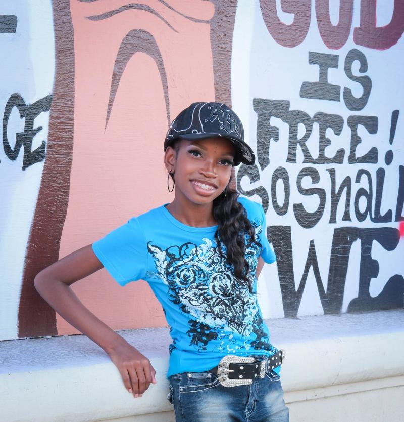 Girl leaning on a ledge in front of a hand-lettered mural