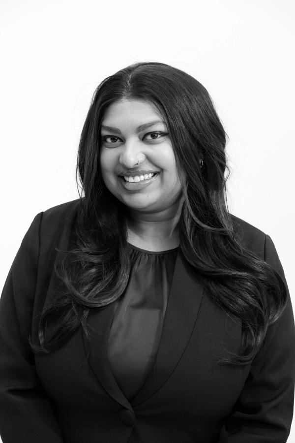 Black and white studio headshot of a smiling woman in a blazer