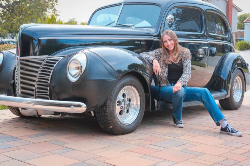 Young woman sitting on the running board of a vintage black car