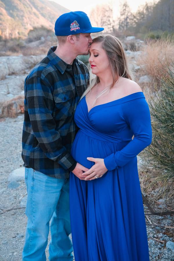 Dad kissing his partner’s forehead as she holds her bump
