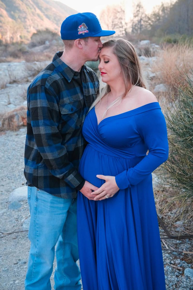 Dad kissing his partner’s forehead as she holds her bump