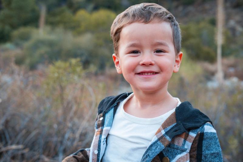 Smiling little boy in a plaid flannel in golden evening light