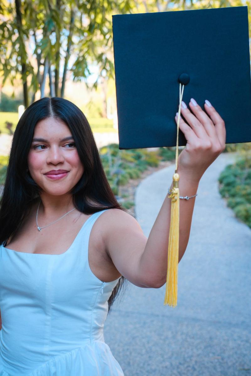 Graduate holding her mortarboard up beside her smile