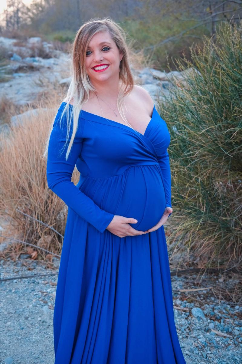 Smiling mom-to-be cradling her bump among desert plants