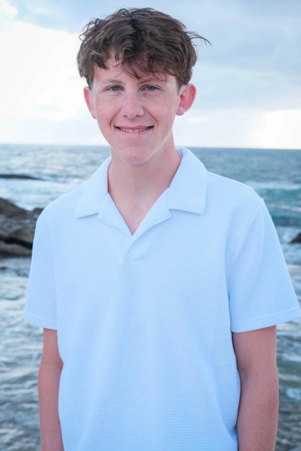 Smiling senior in a white polo standing by the ocean