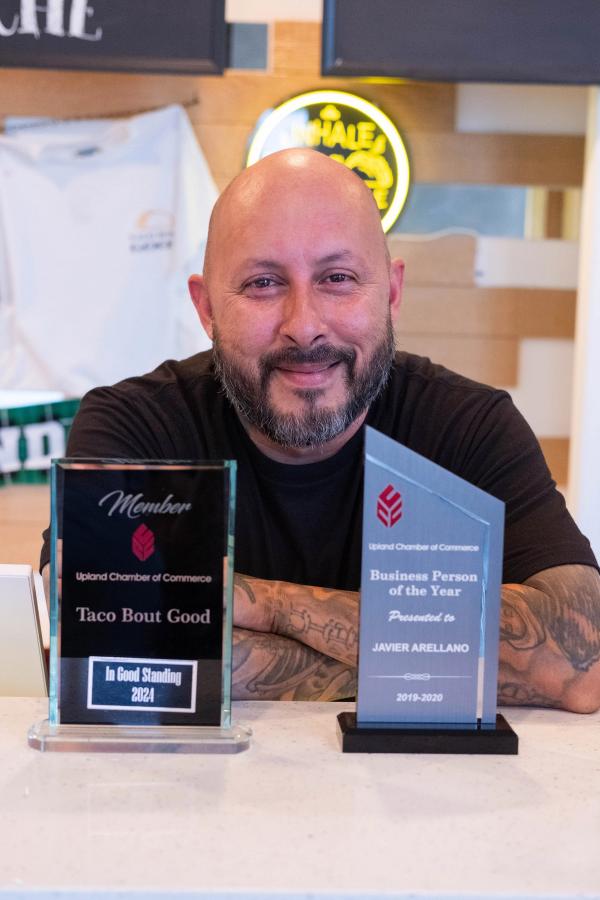 Smiling owner at the counter with his business awards