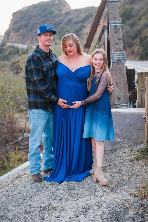 Family of three on an old bridge with the mountains behind