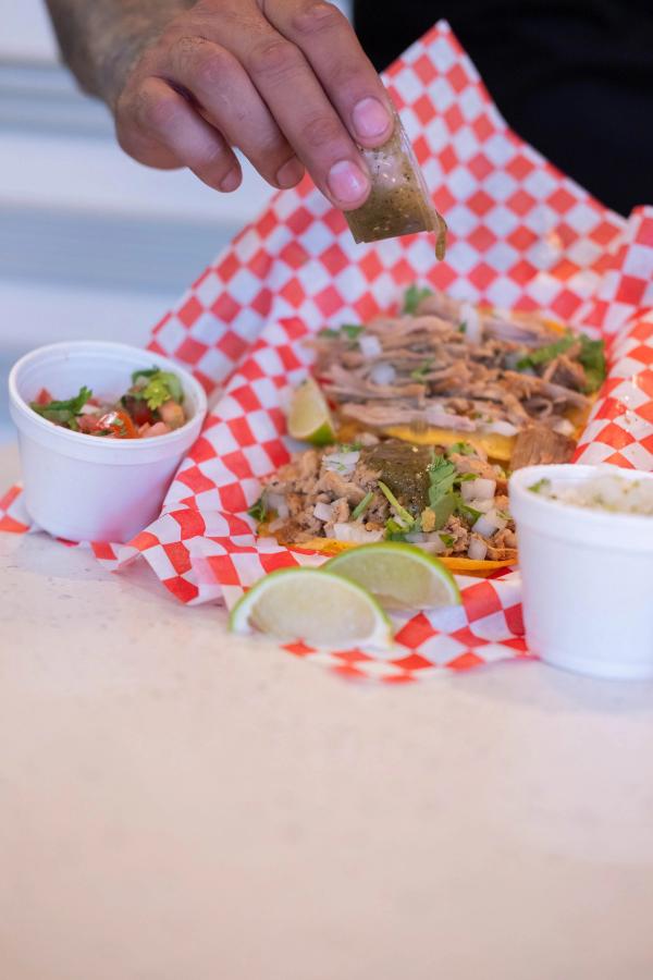 Owner spooning salsa onto a taco plate