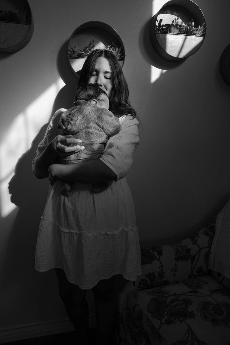Black and white photo of a mother holding her baby in soft light