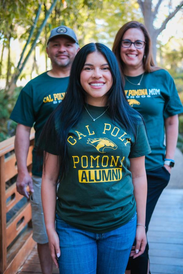 Graduate standing between her proud parents in matching green shirts