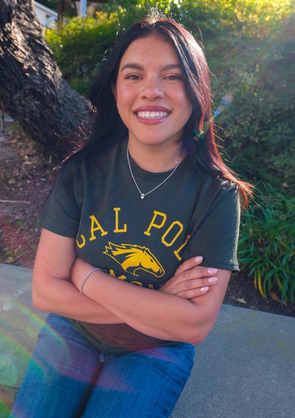 Graduate with arms crossed, laughing in golden afternoon light