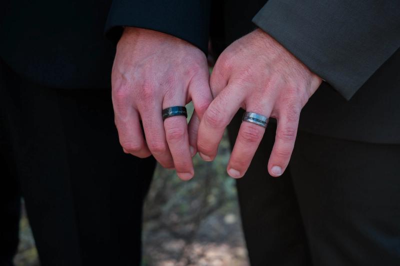 Close-up of the grooms’ hands showing their new wedding bands