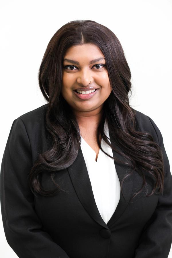 Close studio headshot of a woman in a black blazer and white blouse