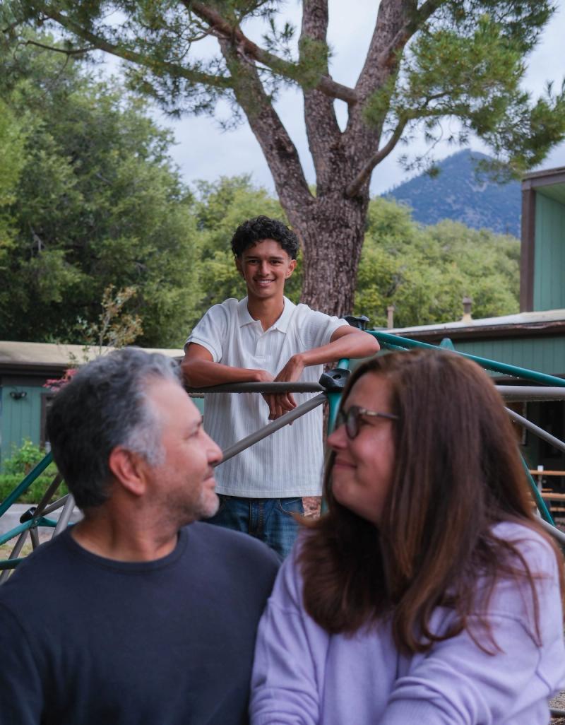 Parents sharing a smile while their son grins over their shoulders