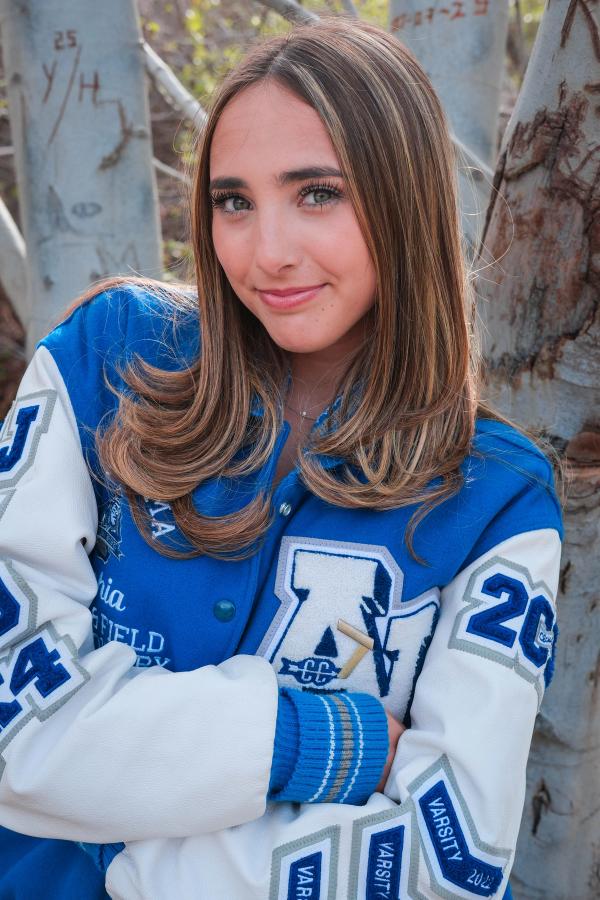 Close portrait of a smiling senior in a blue and white letterman jacket
