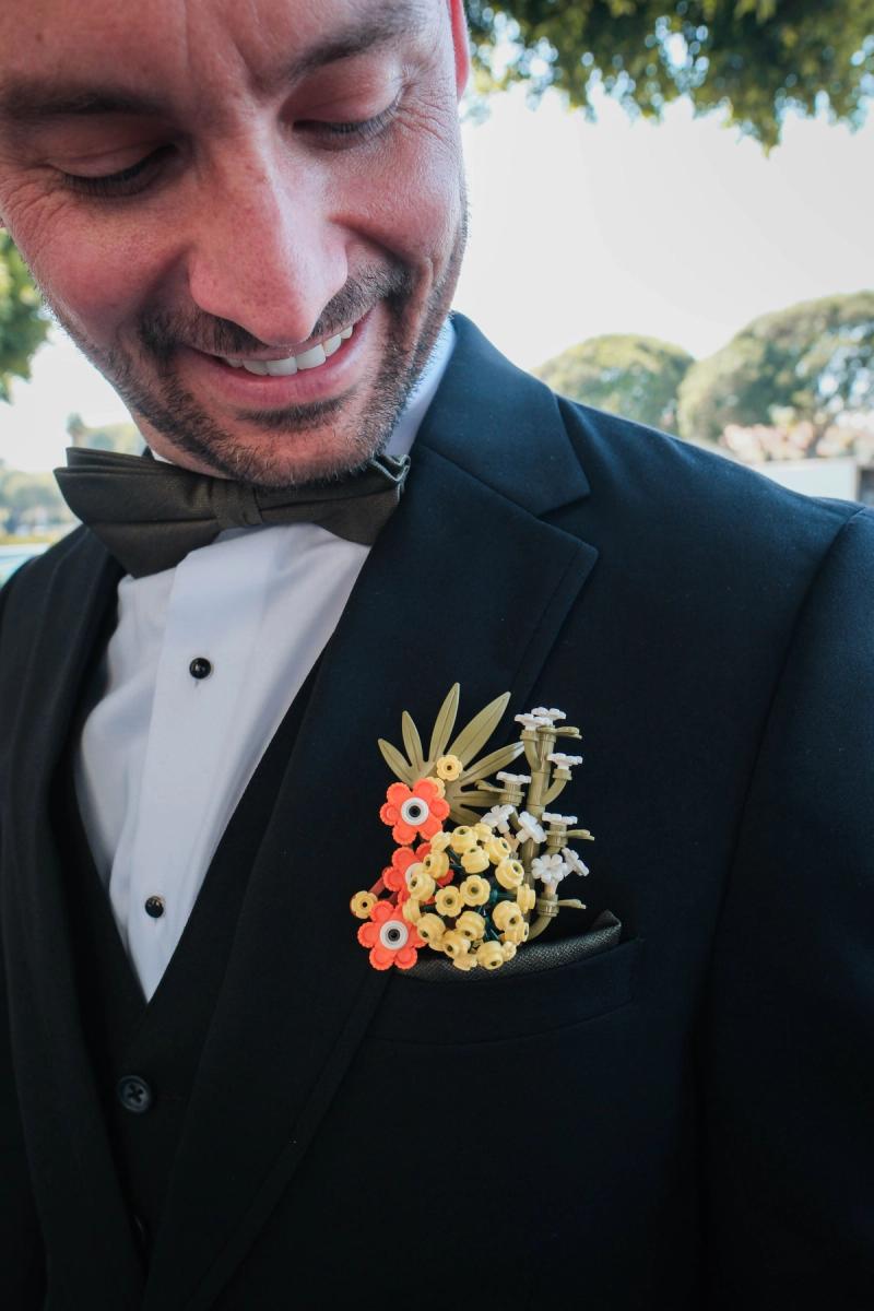 Close-up of a groom laughing as he looks down at his boutonniere