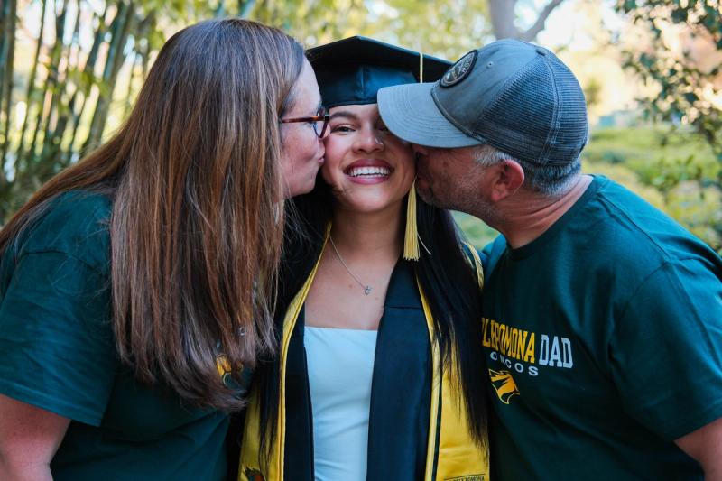 Parents kissing their graduate on both cheeks
