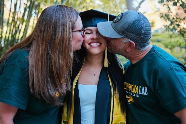 Parents kissing their graduate on both cheeks