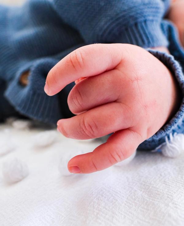 Close-up of a newborn’s tiny hand on a soft blanket