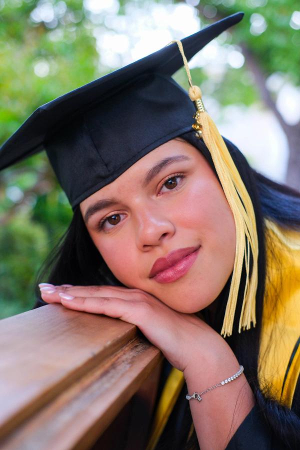 Close portrait of a graduate resting her chin on her hands on a railing