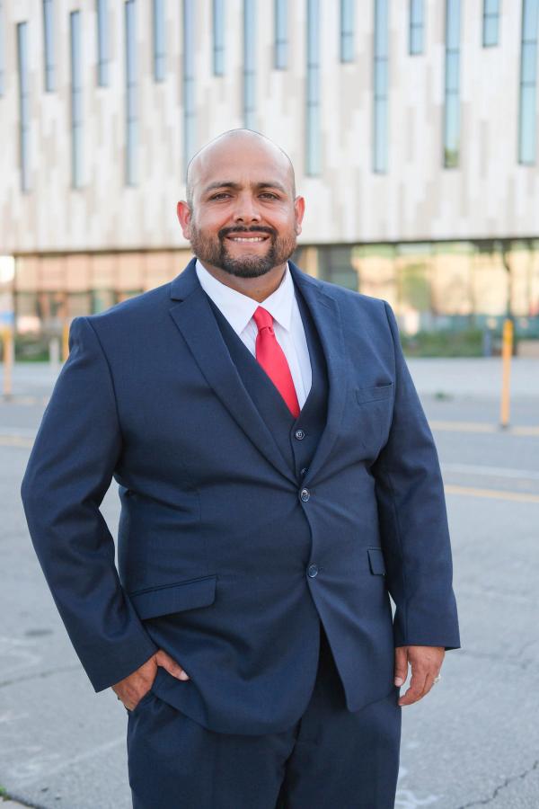 Smiling candidate in a navy suit in front of a modern building