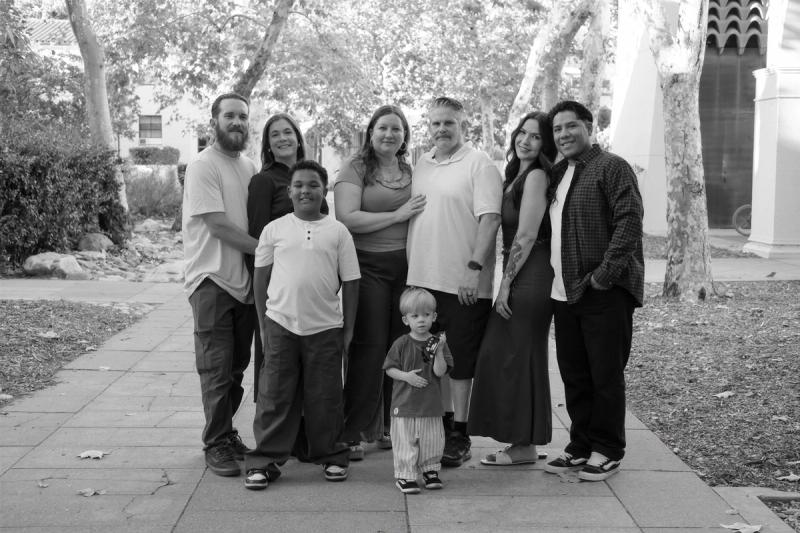 Black and white portrait of the extended family of eight on a tree-lined walkway