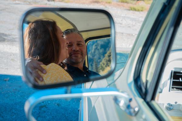 Couple smiling together in the front seat of a blue Mustang