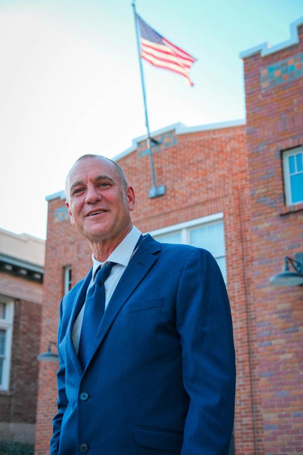 Candidate in front of a brick building with an American flag