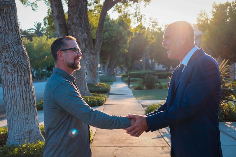 Candidate shaking hands with a resident on a garden walkway