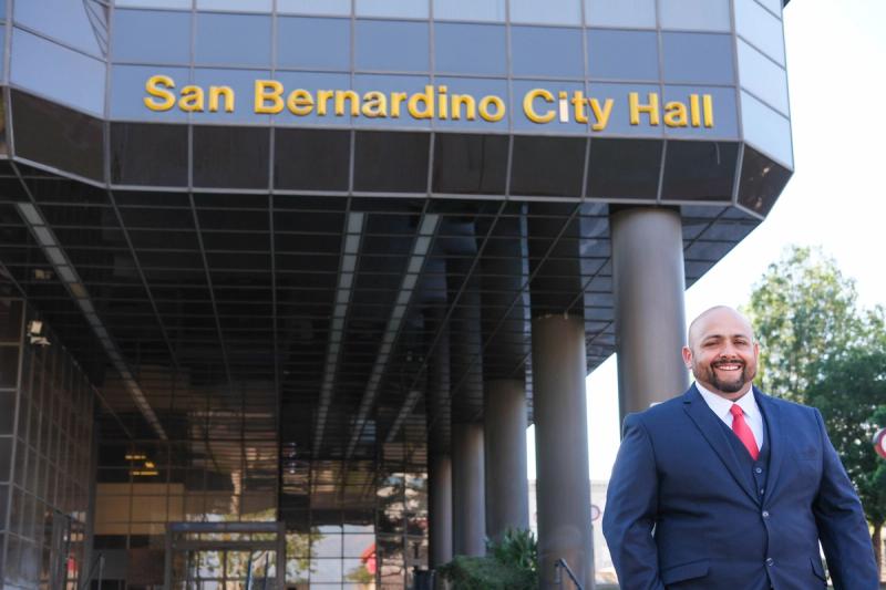 Candidate beside the San Bernardino City Hall sign