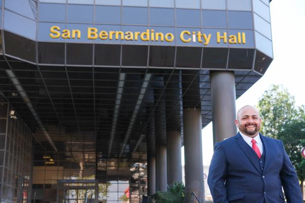 Candidate beside the San Bernardino City Hall sign