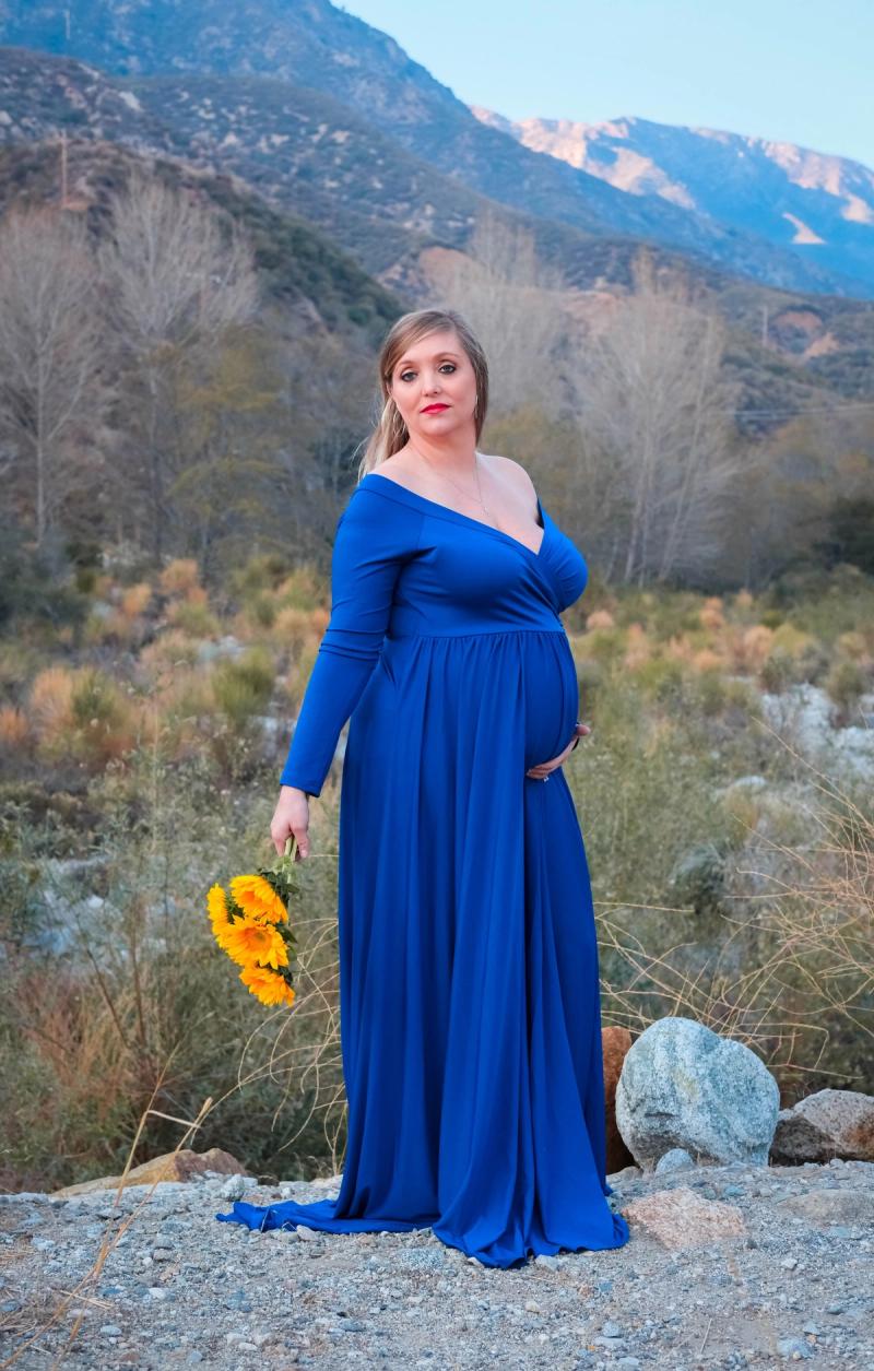 Mom-to-be holding sunflowers with snowy mountains behind her
