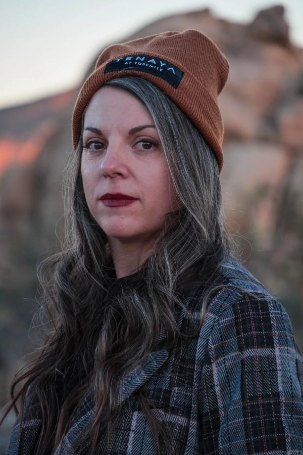 Portrait of a woman in an orange beanie and flannel against desert rocks