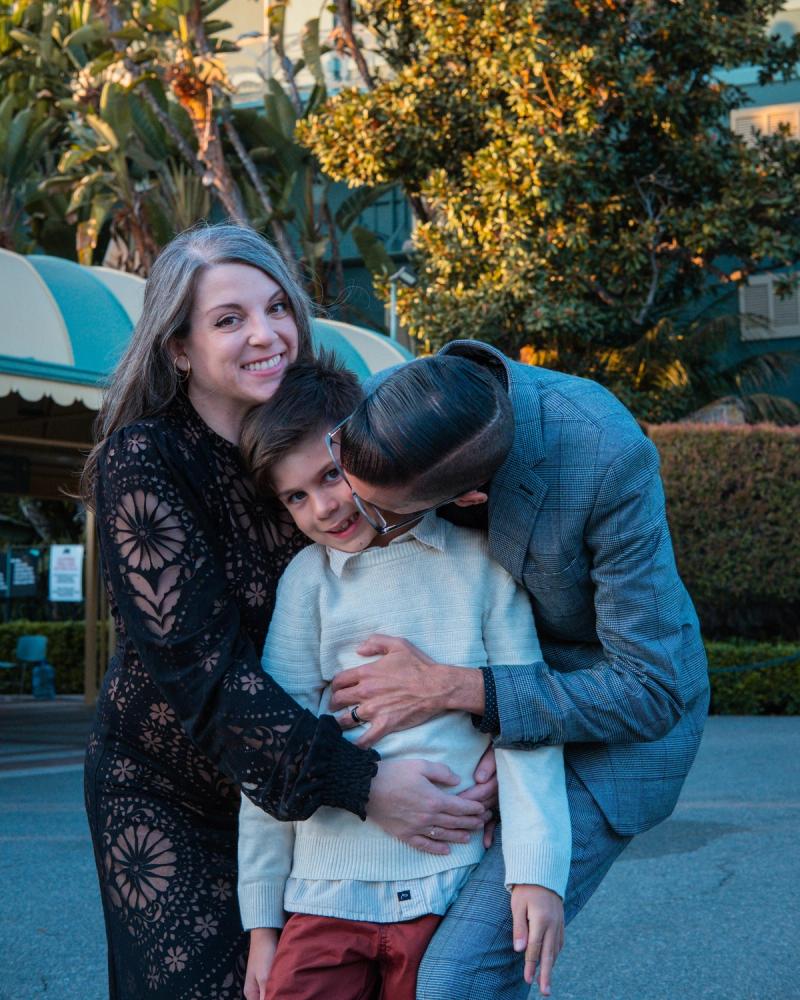 Parents wrapping their son in a hug under the racetrack palms