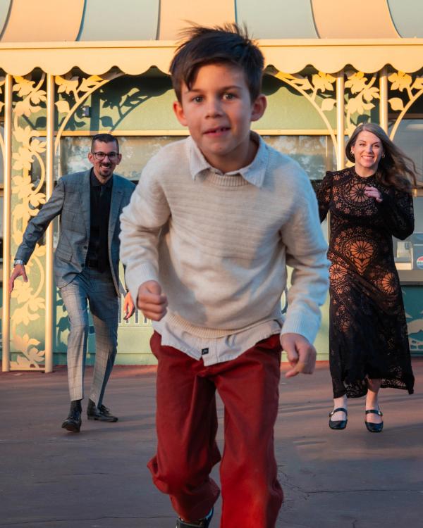 Boy running toward the camera with his parents behind him at Santa Anita Park