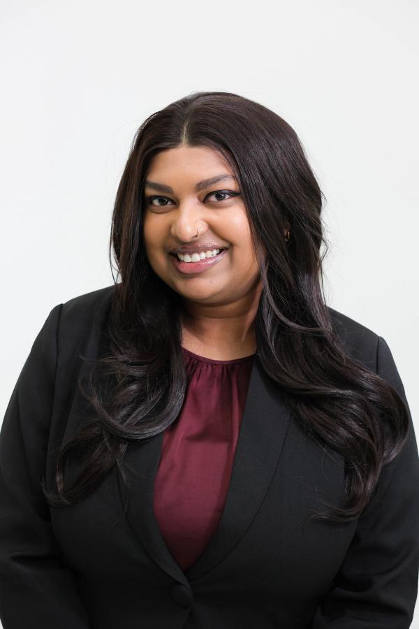 Smiling studio headshot of a woman in a black blazer and burgundy blouse