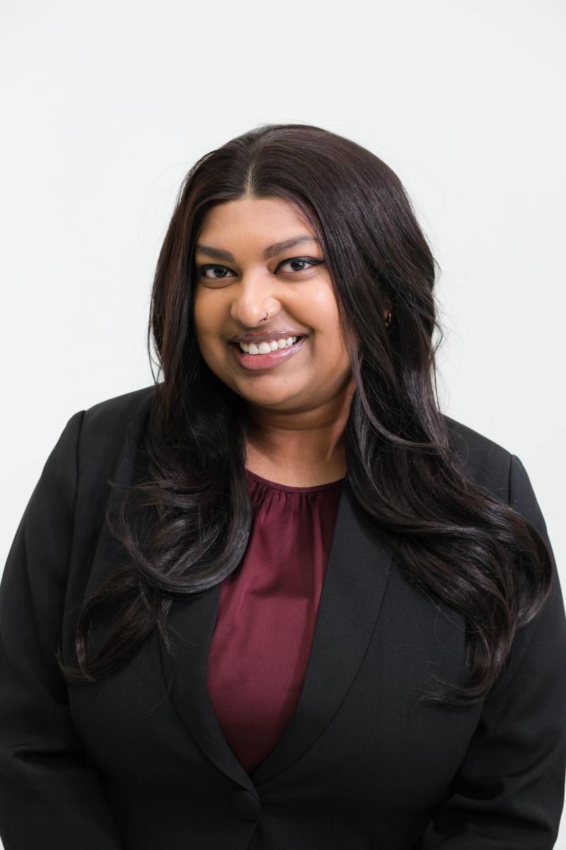 Smiling studio headshot of a woman in a black blazer and burgundy blouse